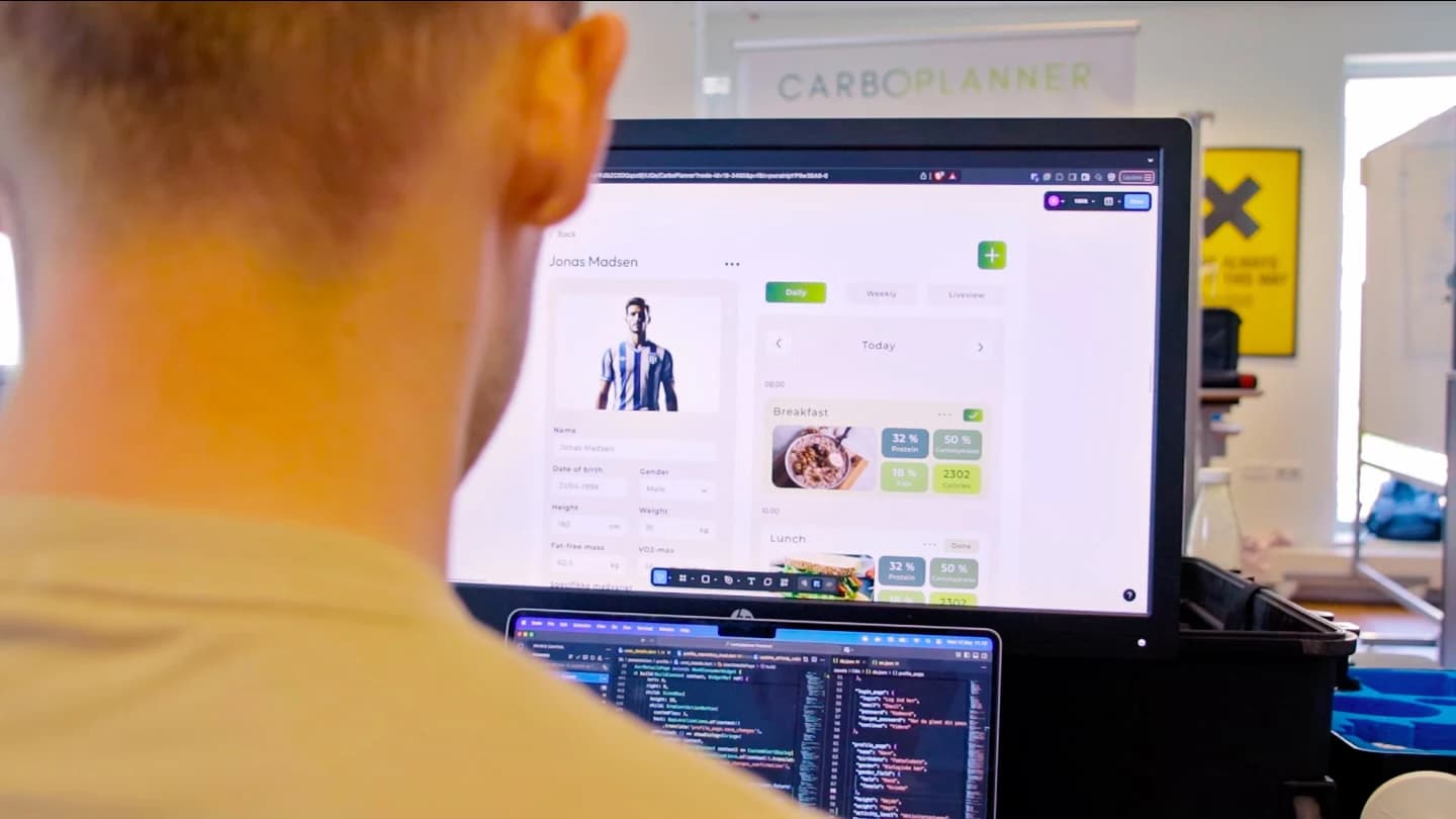Person working on the Carboplanner app with a nutrition dashboard visible on a monitor